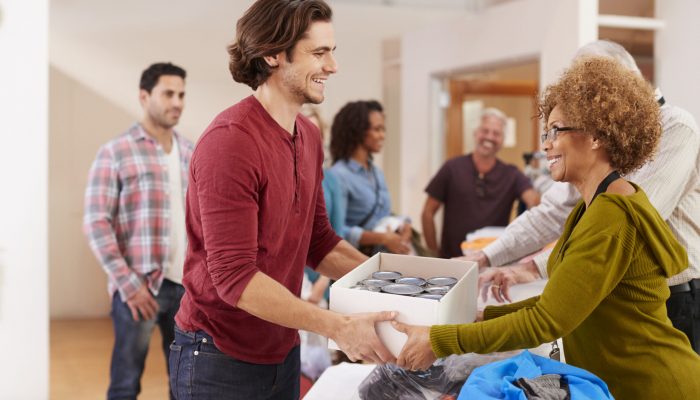 People Donating Food To Charity Food Bank Collection In Community Center