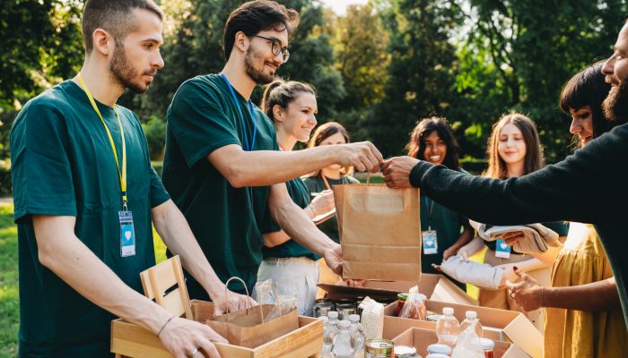 A couple is taking a bag of food at the food and clothes bank. Volunteers are working together at the humanitarian aid project.